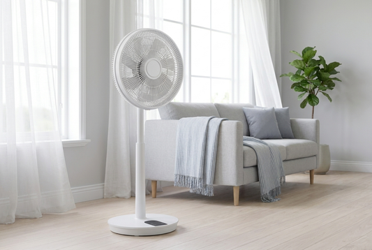 Ventilateur sur pied blanc dans un salon lumineux en été, rideaux légers